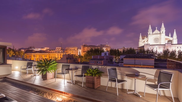 A rooftop terrace with seating, a water feature, and a view of a cathedral.