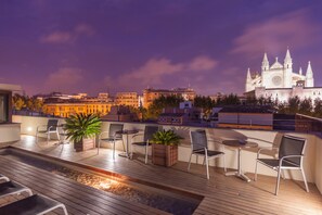 Una terraza en la azotea con mobiliario, una fuente de agua y vistas a una catedral.