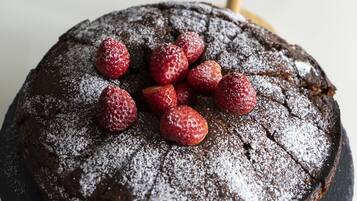 A round chocolate cake with powdered sugar and strawberries on top.