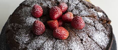 A round chocolate cake with powdered sugar and strawberries on top.