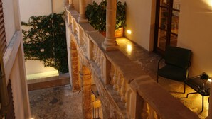 A balcony with stone columns, a chair, and potted plants.
