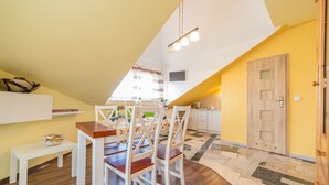 A dining area with a white table and chairs, a small bench, and a bowl of snacks. - Motelik Mister (Mielno)