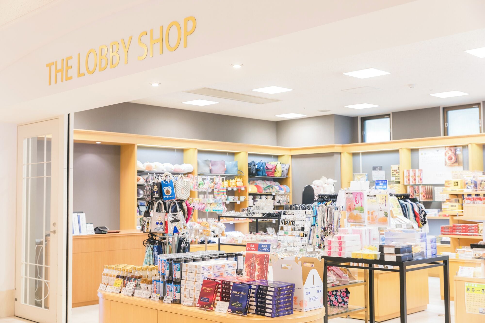 A store named "THE LOBBY SHOP" with shelves of bags, accessories, and food items.
