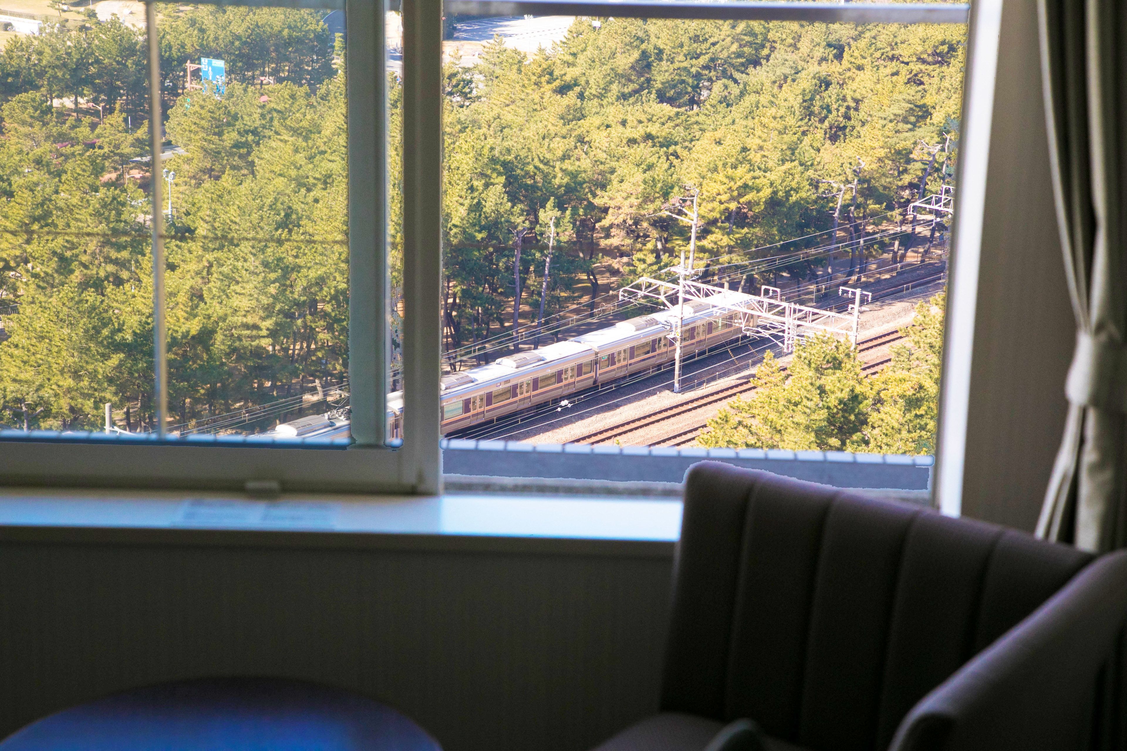 A room with a window overlooking a railway track and trees.