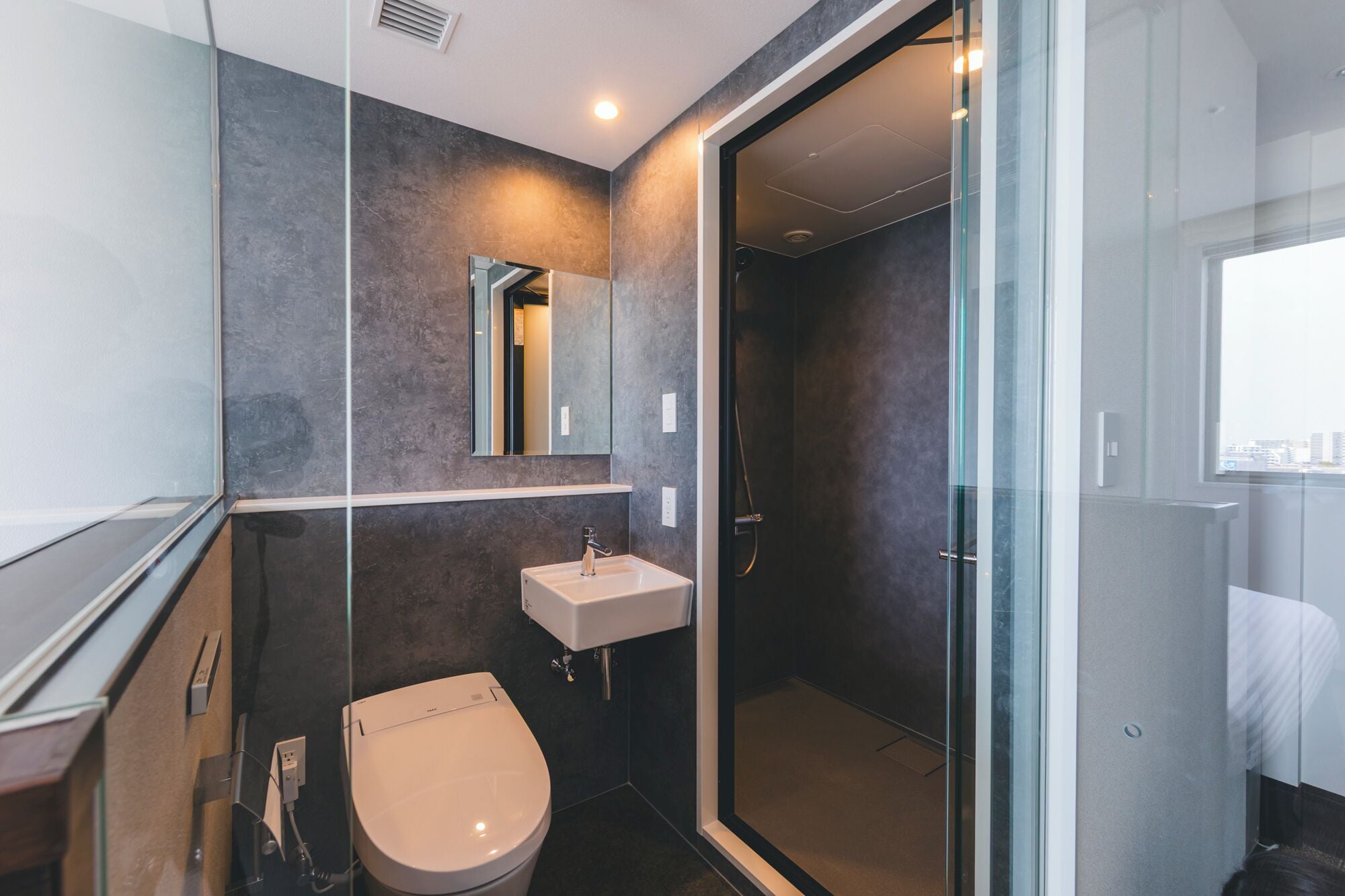 A modern bathroom with a toilet, sink, and glass shower enclosure.