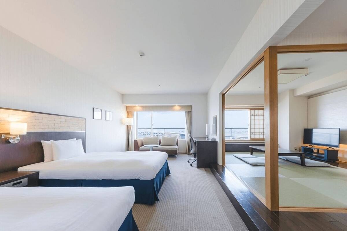 A hotel room with two beds, a desk, a TV, and a large mirror.