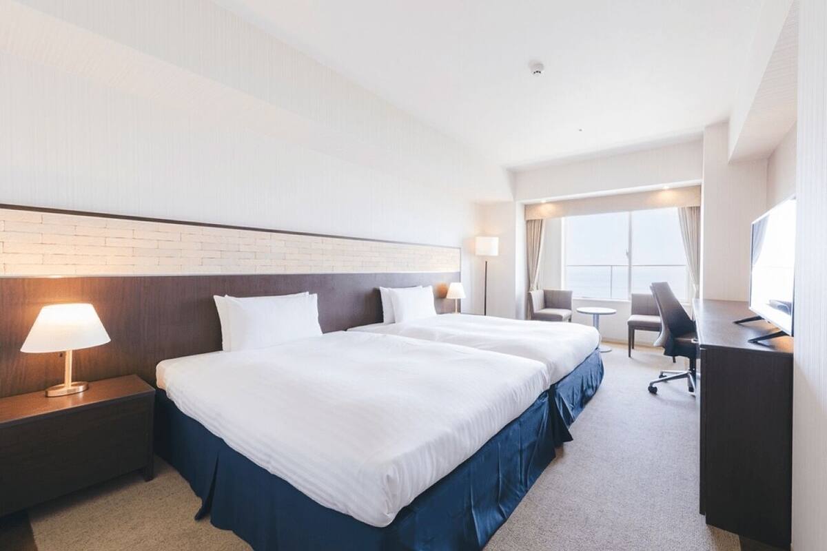 A hotel room with a large bed, a desk, and a chair.