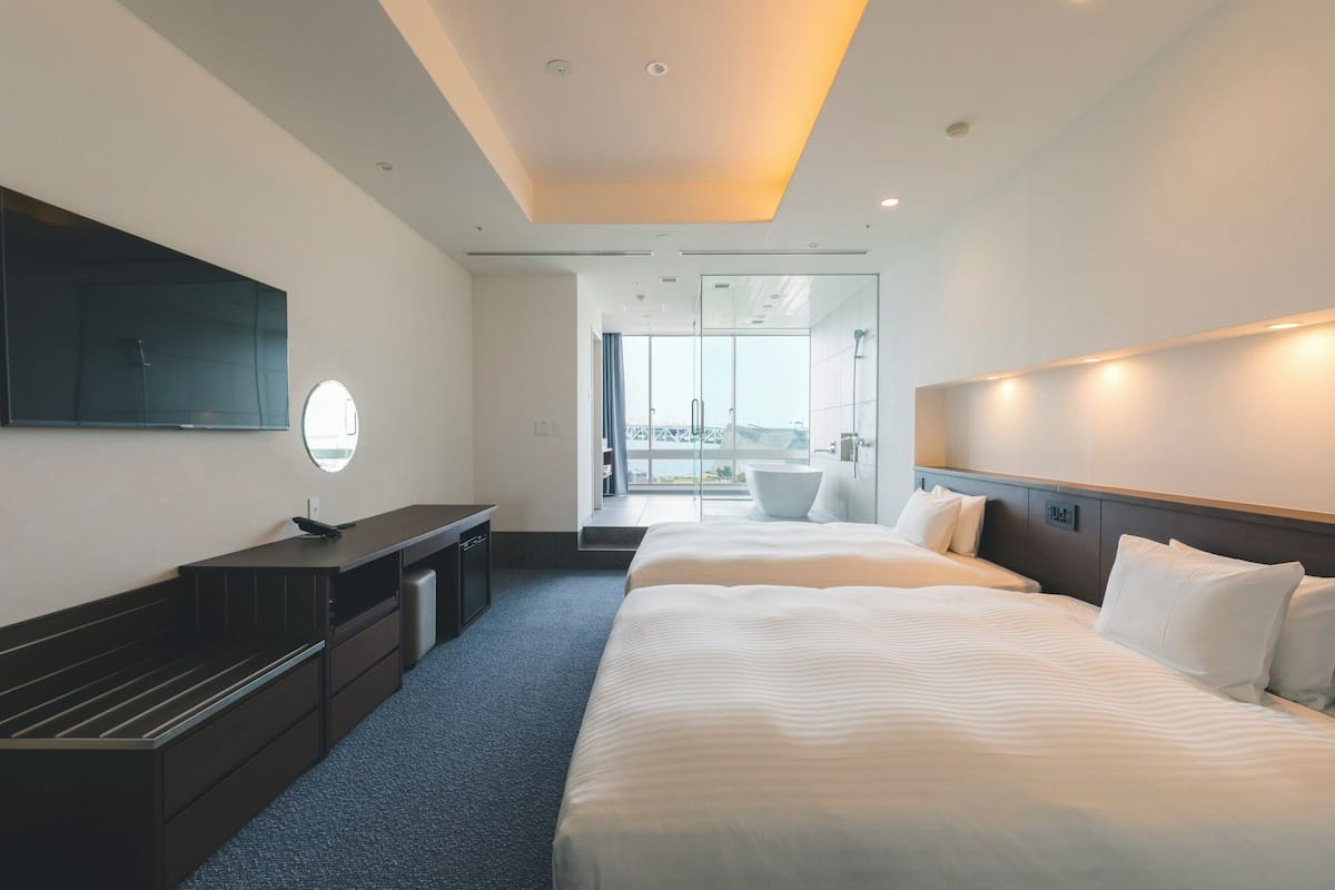 A modern hotel room with a large bed, a desk, and a TV.