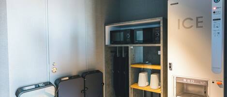 A compact hotel room with a minibar, a microwave, and an ice dispenser.