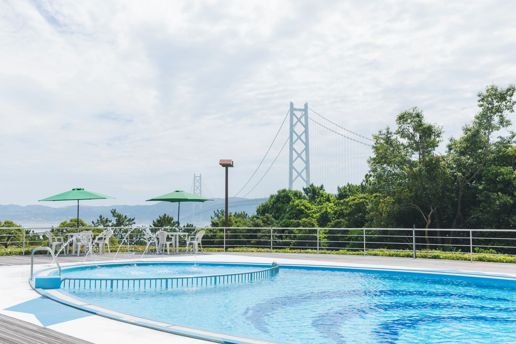 A swimming pool with a view of a bridge and mountains in the background.
