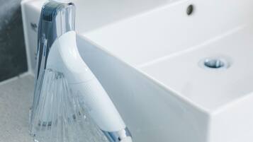 A modern bathroom with a white sink and a handheld showerhead.