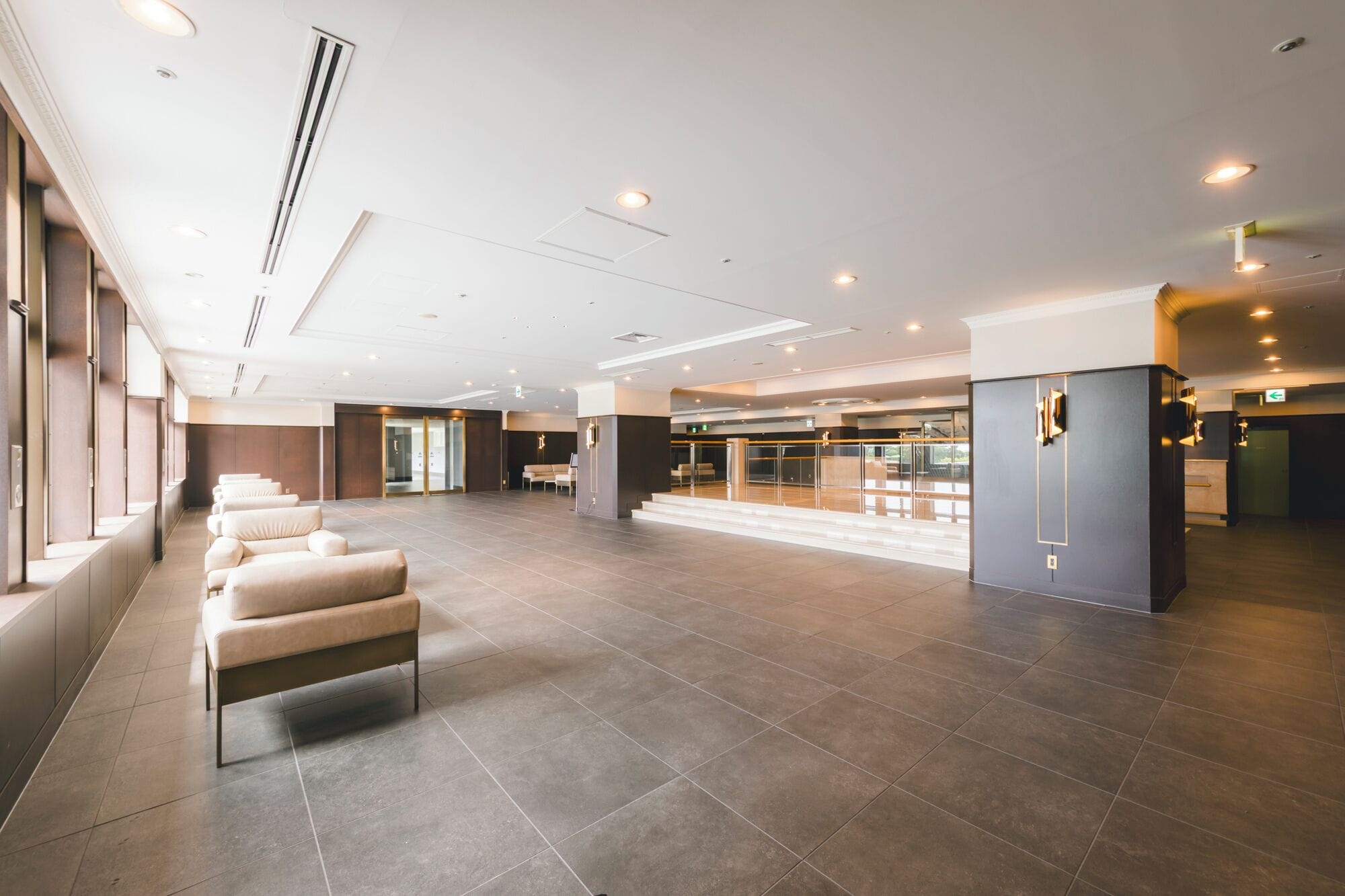 A spacious lobby with a seating area, a reception desk, and a glass partition leading to a waiting area.