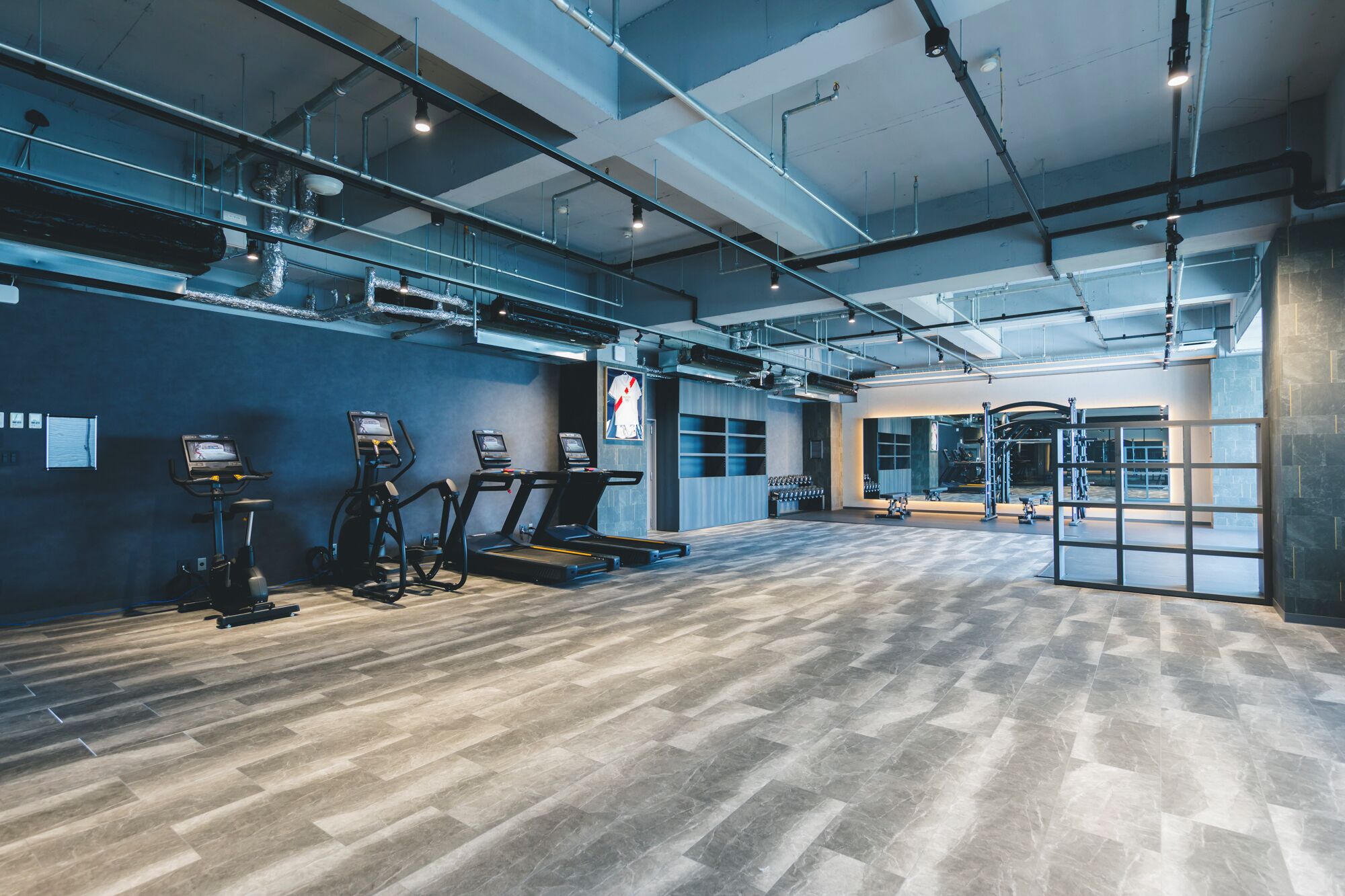 Een ruime fitnessruimte met loopbanden, elliptische trainers en gewichten.