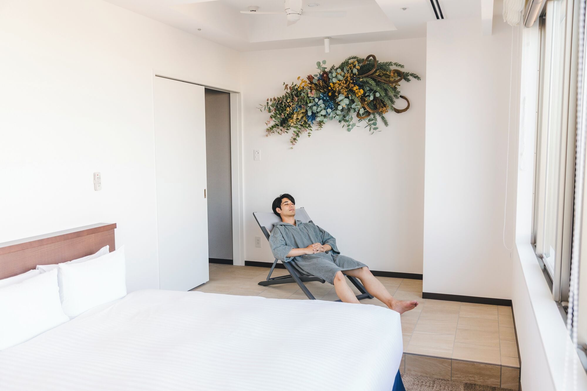 Une chambre d’hôtel moderne avec un lit, un fauteuil inclinable et un mur végétal décoratif.