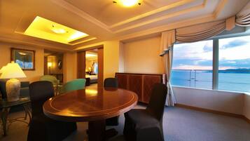 Habitación de hotel con una mesa redonda, cuatro sillas, una lámpara, un cuadro y vista al mar.