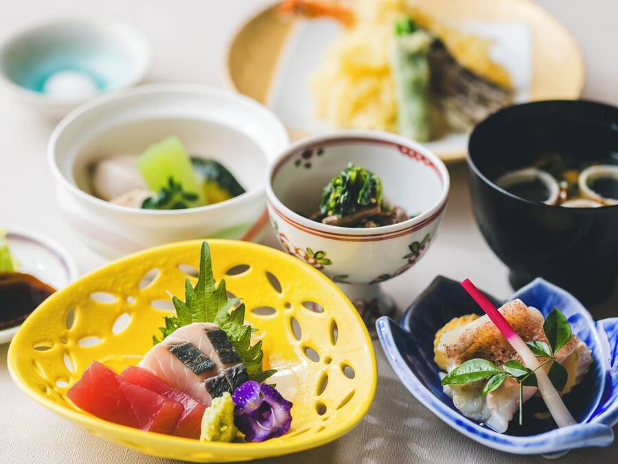A variety of Japanese dishes including sashimi, sushi, and bowls of soup.