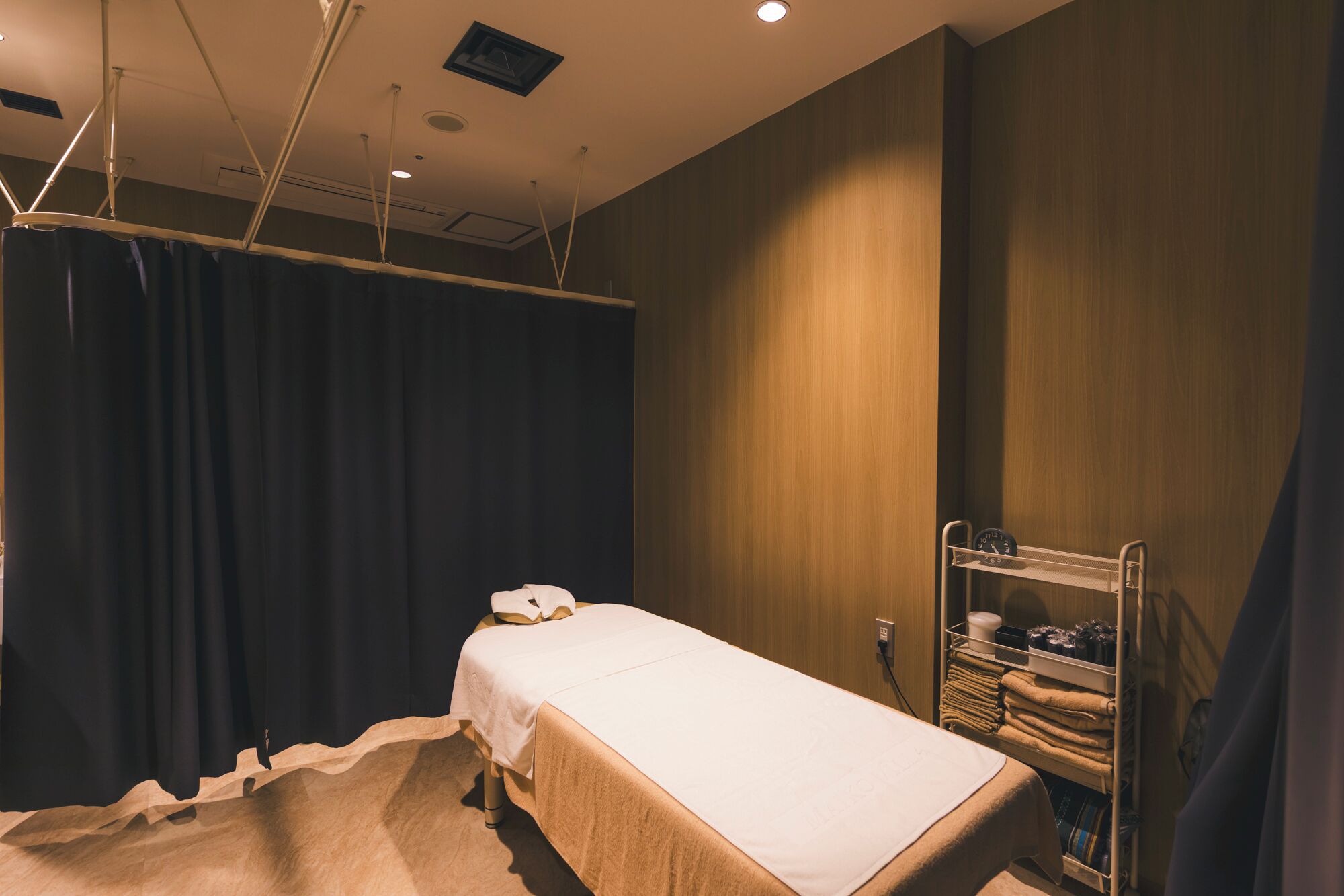 Una habitación de hotel con una cama, un estante con toallas y una cortina.