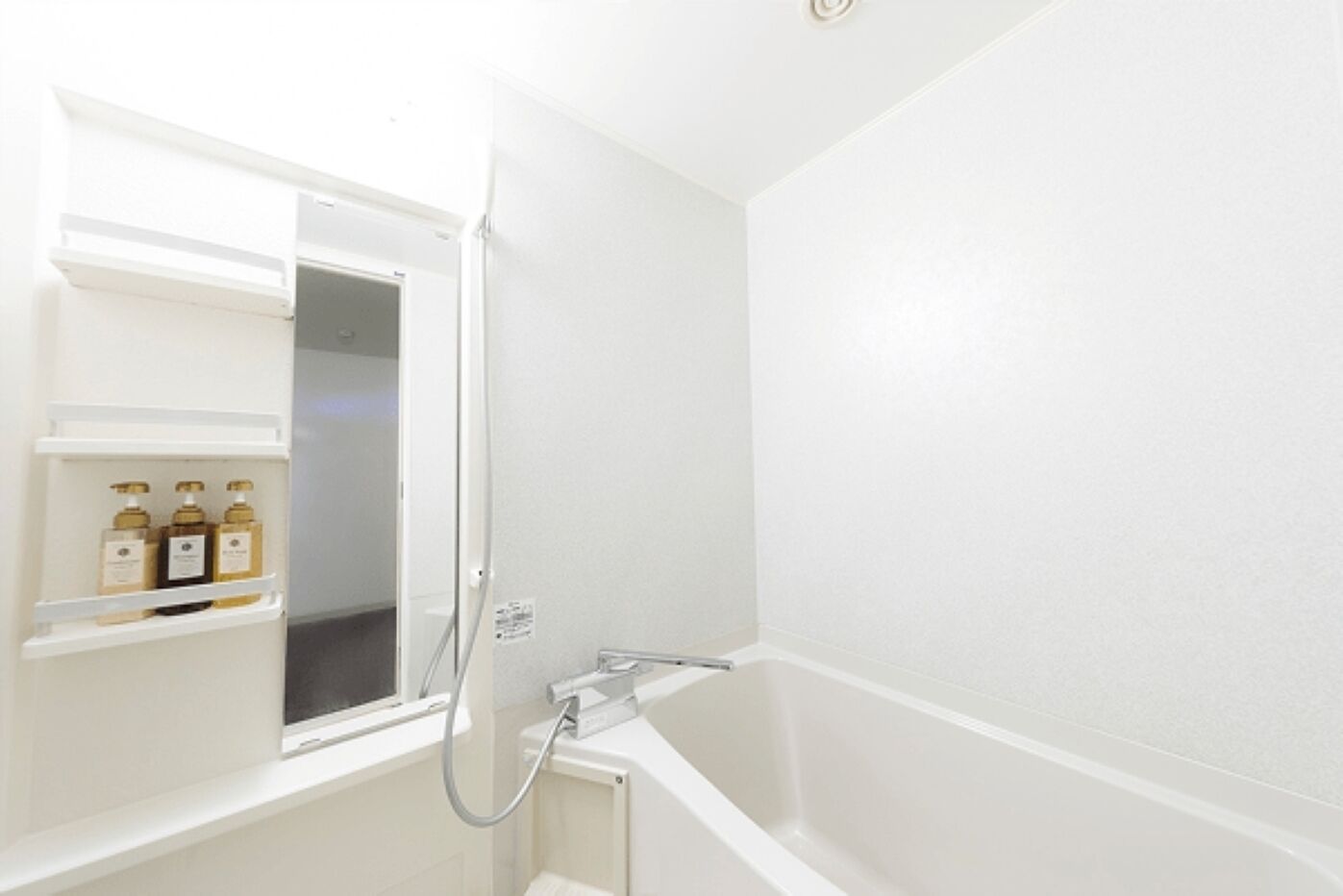 Un baño con ducha, inodoro y un estante con artículos de aseo.