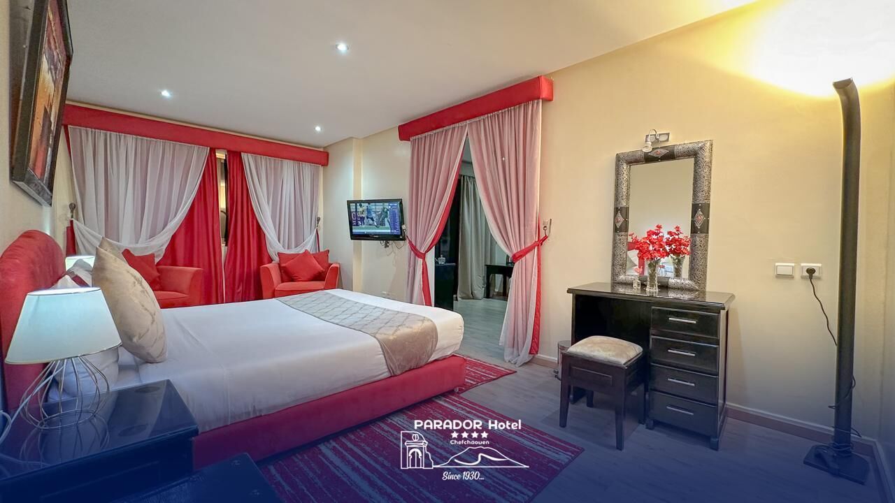 A hotel room with a bed, a desk, a dresser, a TV, and a mirror.