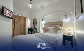 A hotel room with a large bed, a nightstand, a mirror, and a television.