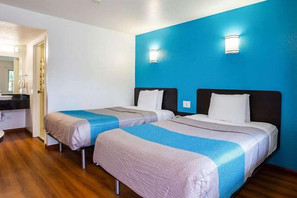 Une chambre d’hôtel avec deux lits, un mur d’accent bleu et un plancher en bois.