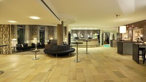 Een hotel lobby met een receptiebalie, een zithoek en een bar.