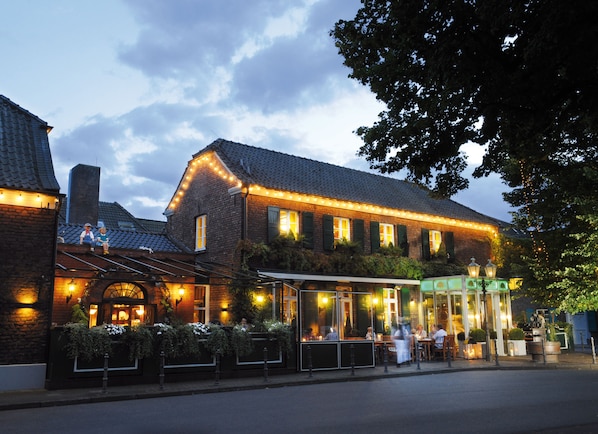 A traditional brick building with a covered outdoor seating area and a visible entrance.
