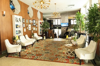 A room with wooden flooring, colorful yoga mats, a large tropical leaf mural, and various potted plants. at Hotel Croydon