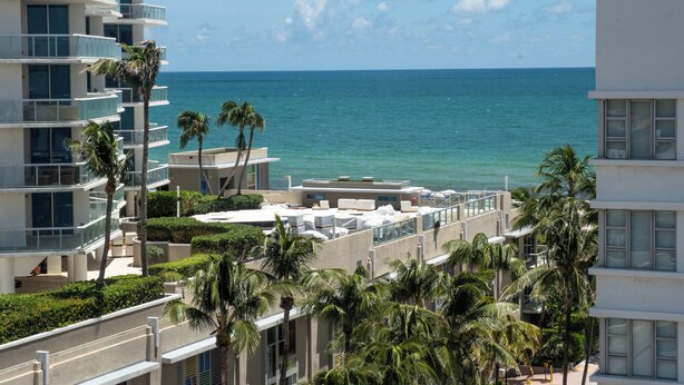 A high-rise hotel with multiple balconies overlooking a beach. - Hotel Croydon (Miami Beach)