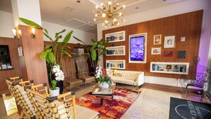 A hotel lobby with a wooden wall, a large TV, and a reception desk. - Hotel Croydon (Miami Beach)