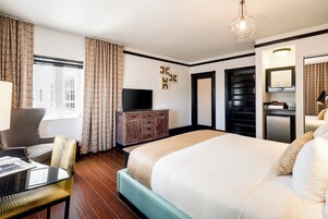 Una habitación de hotel con una cama grande, un televisor, un escritorio con una silla y un aparador.