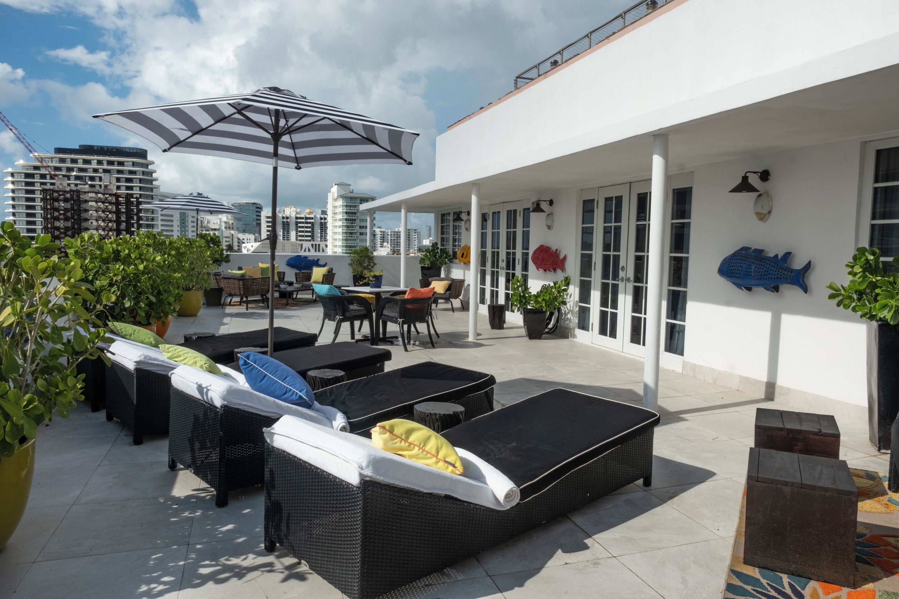 Eine Dachterrasse mit Sitzgelegenheiten im Freien, darunter Korbs Sofas und ein Tisch mit Stühlen.