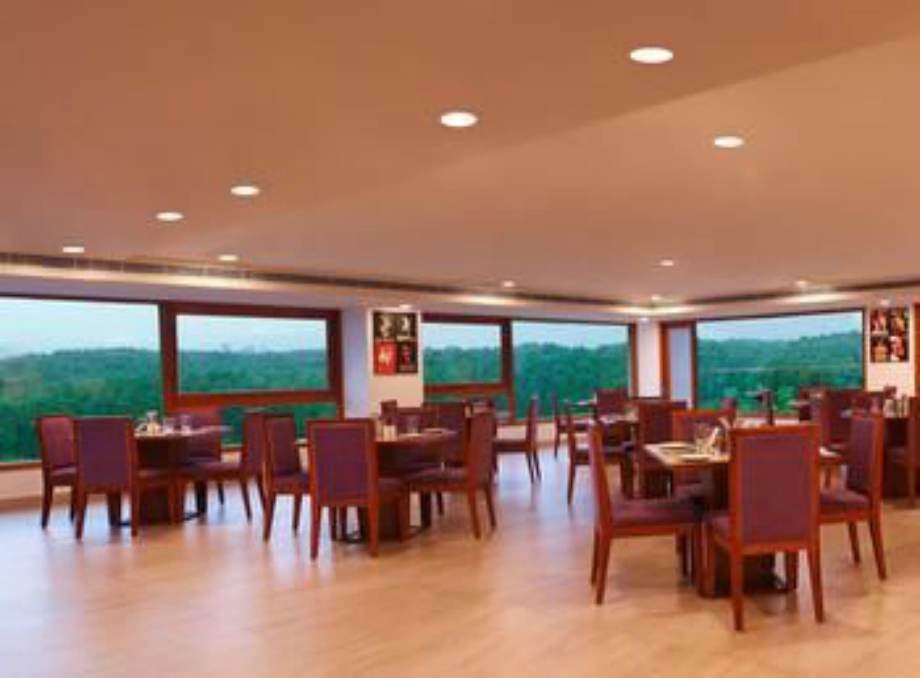 A spacious dining area with wooden tables and chairs, large windows offering a view of the outdoors.