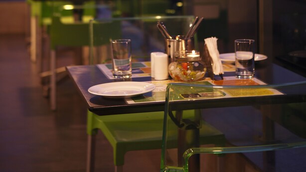 Une table à manger dressée pour deux personnes, avec en arrière-plan une vue sur le paysage urbain.