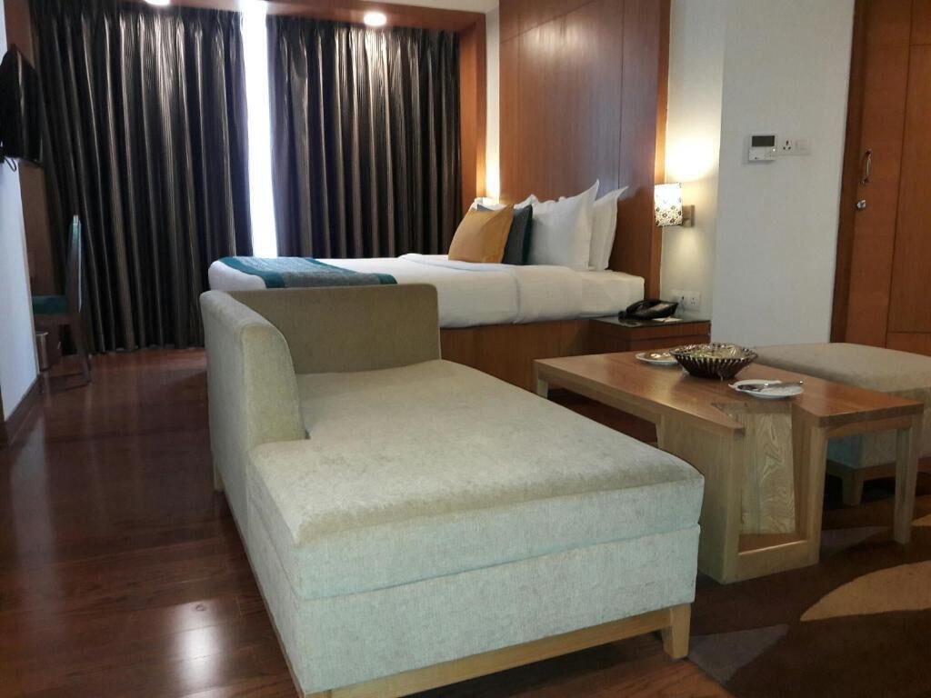 Una habitación de hotel con una cama, un sofá, una mesita y un escritorio.