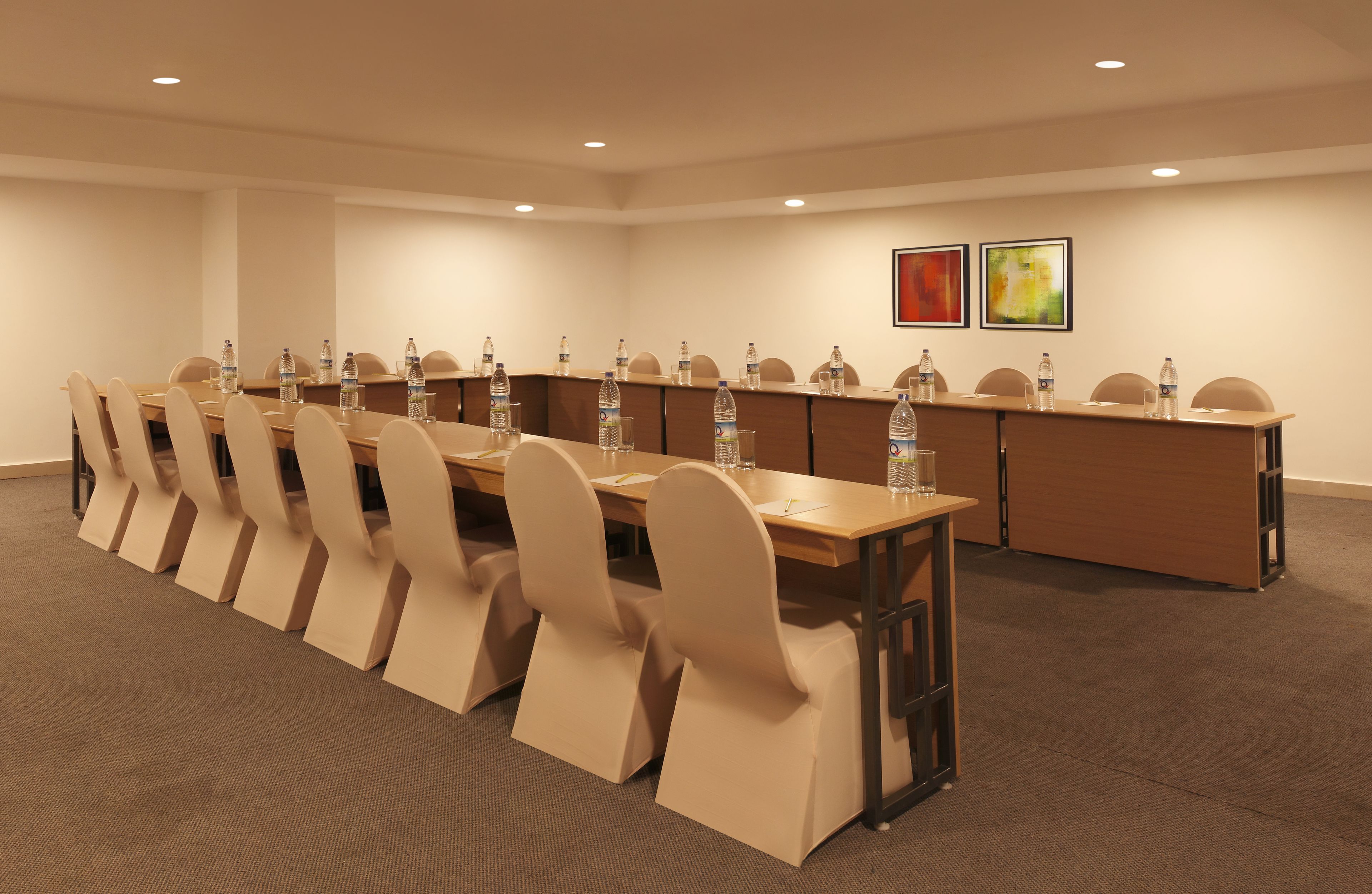 A conference room with a long table, beige chairs, and water bottles.