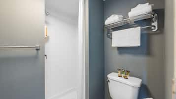 A bathroom with a shower, a toilet, and a towel rack with towels.