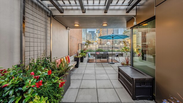 A covered patio with a seating area, potted plants, and a view of the cityscape. - Hotel Willo (formerly YWCA Hotel Vancouver) (Vancouver)