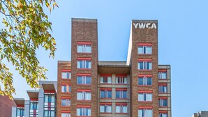 A multi-story hotel with a prominent 'YWCA' sign, featuring a brick facade, multiple windows, and a central entrance with a red awning. - Hotel Willo (formerly YWCA Hotel Vancouver) (Vancouver)