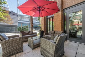 An outdoor patio area with wicker furniture and a red umbrella. - Hotel Willo (formerly YWCA Hotel Vancouver) (Vancouver)
