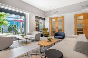 A modern hotel lobby with a seating area, a wooden cabinet with glass doors, and a large window overlooking the street. - Hotel Willo (formerly YWCA Hotel Vancouver) (Vancouver)