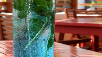 A glass of blue beverage with mint leaves, labeled 'ARANWA HOTELS RESORTS & SPAS', on a wooden table.