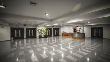 Un hall d’entrée spacieux avec un sol à carreaux, un comptoir de réception et une grande plante en pot.