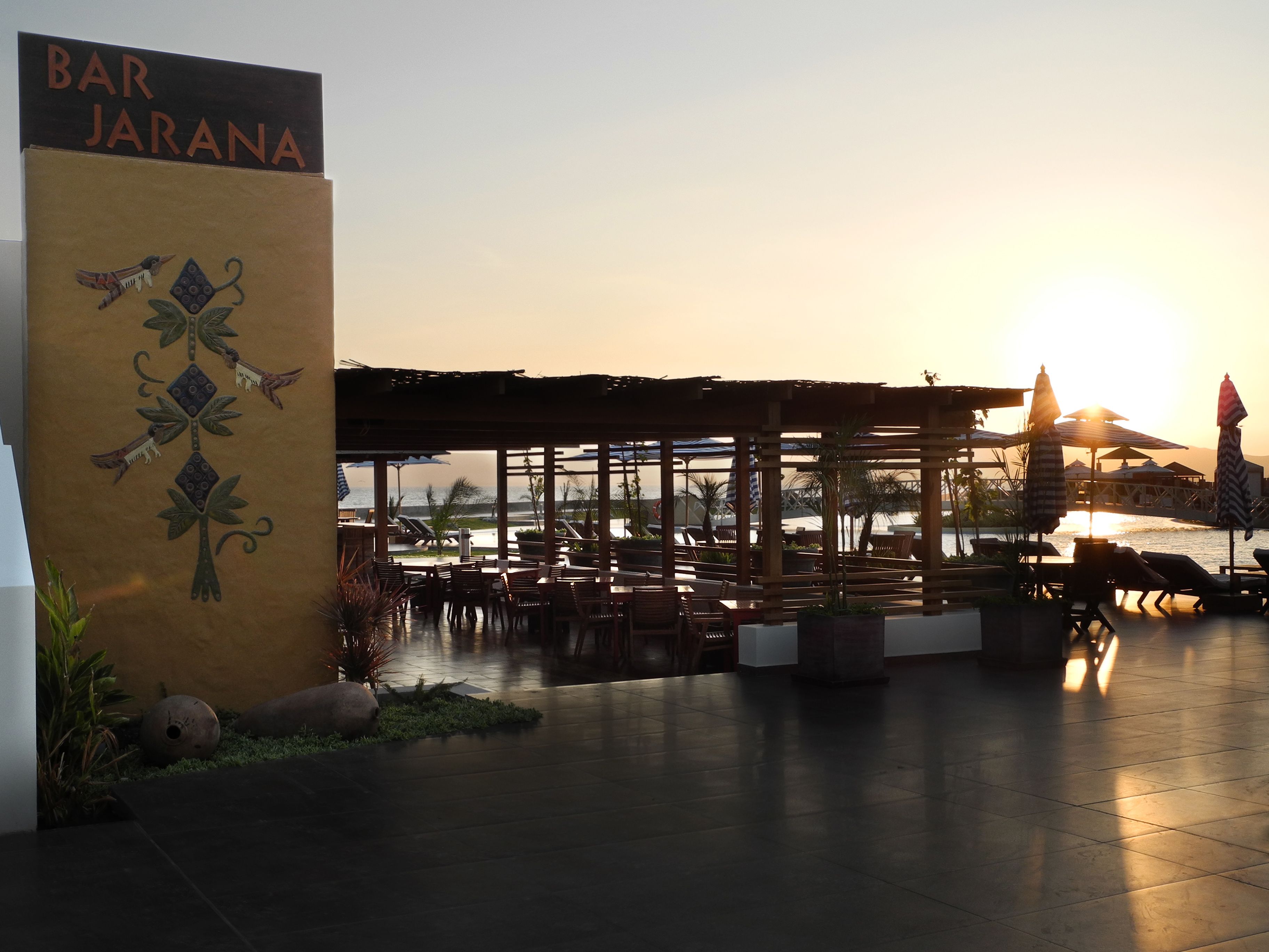 A beachfront bar named BAR JARANA with outdoor seating and a view of the ocean.