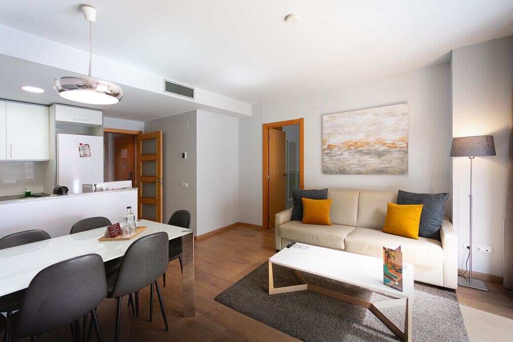 Un salon moderne avec un canapé blanc, une table basse et un coin repas comprenant une table et des chaises blanches.