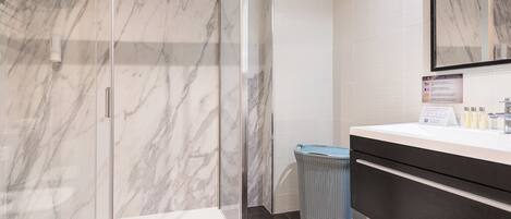 A modern bathroom with a glass-enclosed shower, a white sink, and a large mirror.