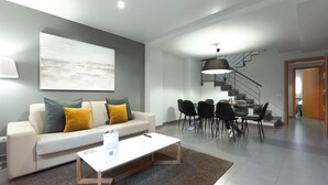 Een moderne woonkamer met een bank, salontafel en een eethoek met stoelen en een tafel.