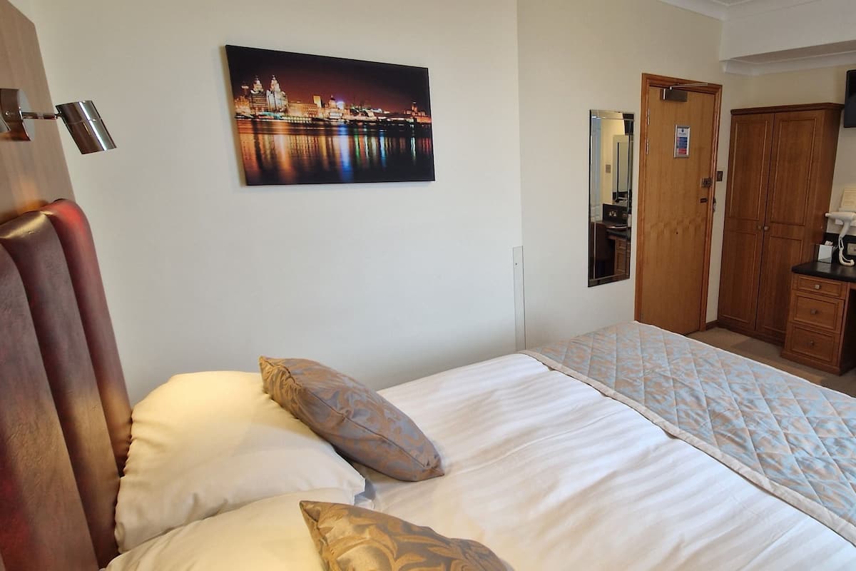 A hotel room with a bed, a desk, a chair, a TV, and a bathroom.