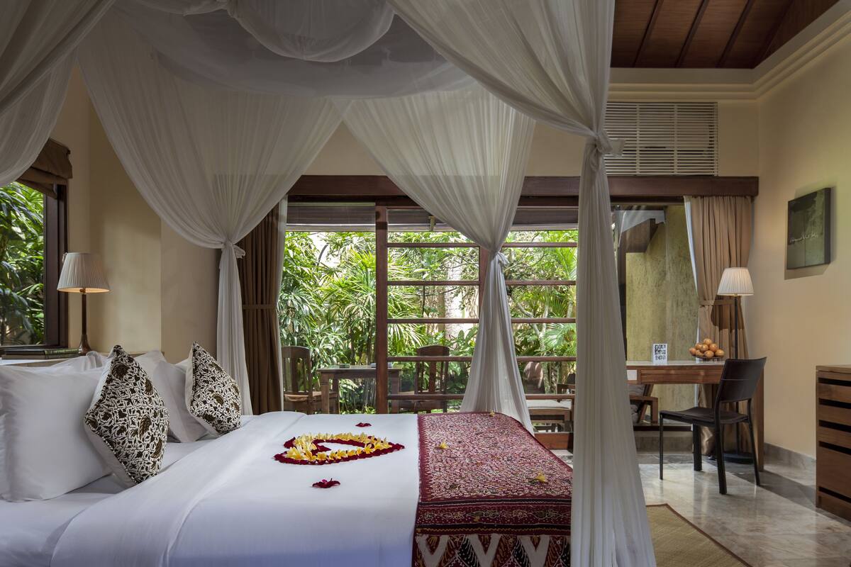 Une chambre d’hôtel avec un lit, un bureau et une vue sur la verdure.