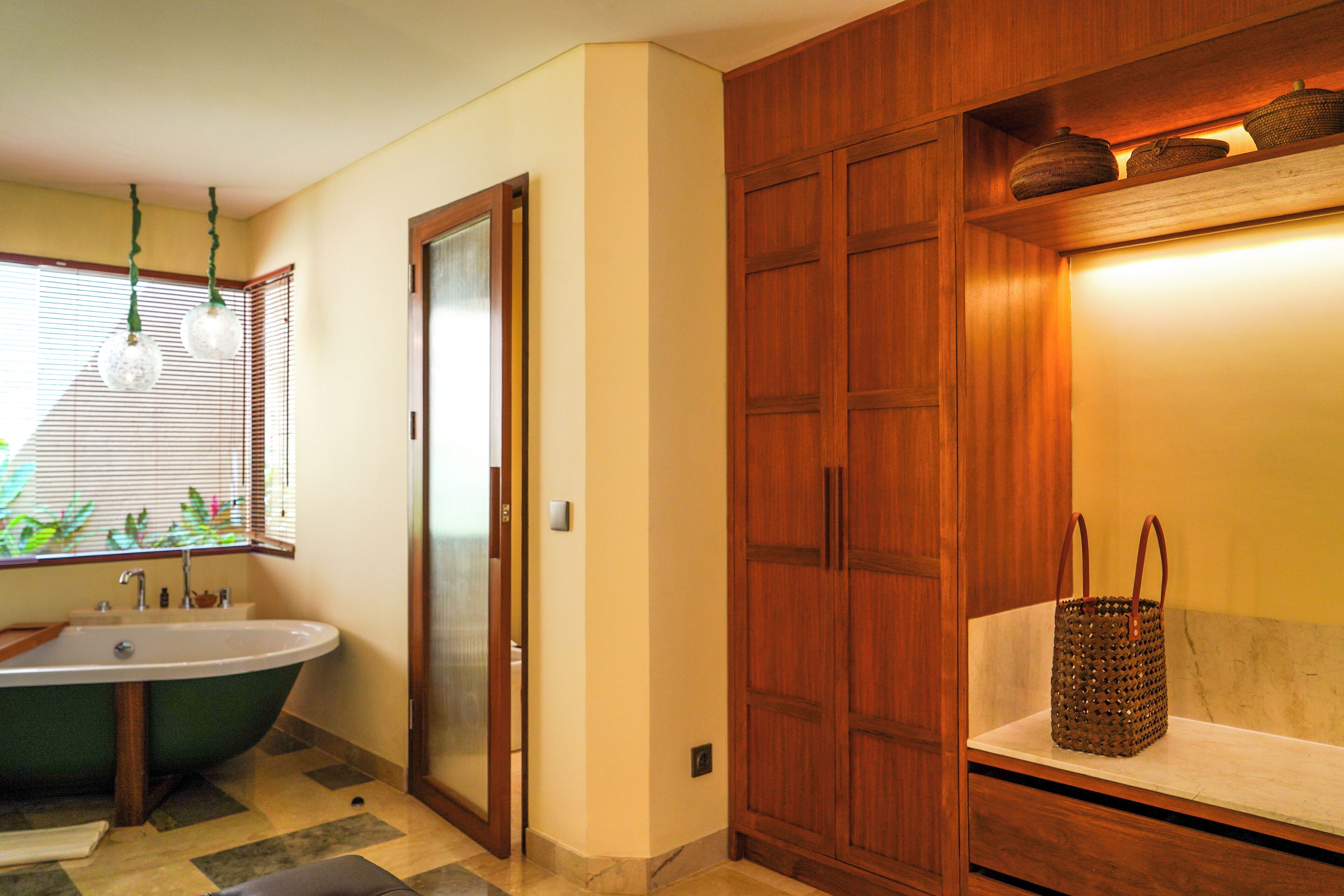 Un baño con una bañera independiente, un tocador con espejo y un mueble de madera con una cesta encima.